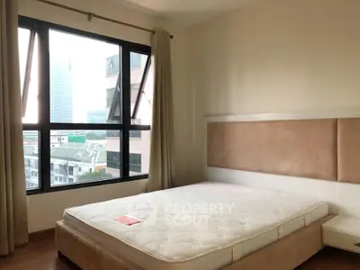 Spacious bedroom with large windows offering city views, featuring a comfortable bed and modern decor.