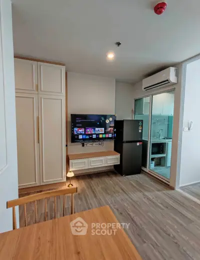 Modern living room with TV, fridge, and air conditioning in a stylish apartment.