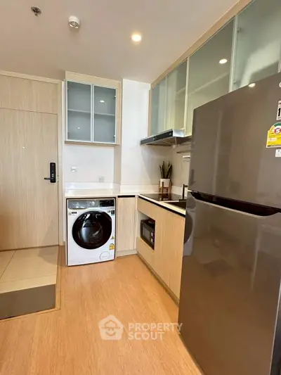 Modern kitchen with sleek appliances and wooden cabinetry in a compact layout.