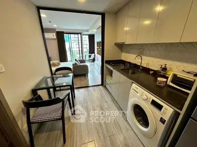 Modern apartment kitchen with washing machine and open layout to living room.
