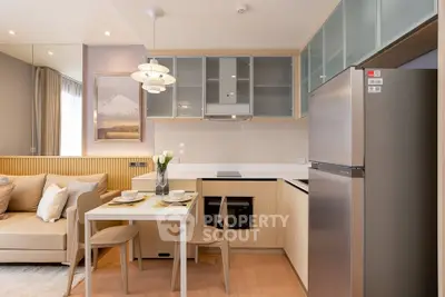 Modern kitchen with sleek cabinetry, dining area, and cozy living space in open layout apartment.