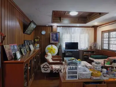 Charming living room with wooden paneling and cozy decor, featuring a TV and ample storage space.