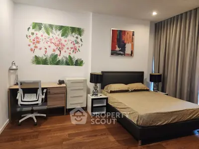 Modern bedroom with stylish decor and workspace, featuring wooden flooring and elegant curtains.