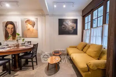 Charming living room with cozy yellow sofa and elegant dining area, featuring artistic wall decor.