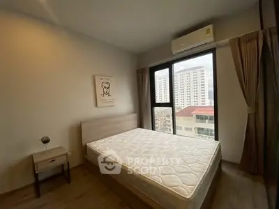 Modern bedroom with large window and city view, featuring a comfortable bed and stylish decor.