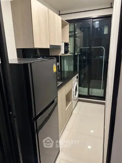 Modern kitchen with sleek appliances and balcony view in urban apartment