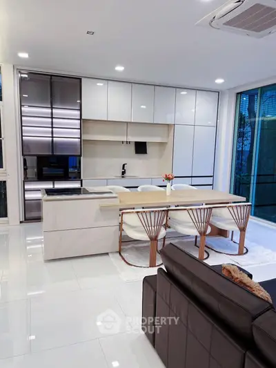 Modern kitchen with sleek design and open layout, featuring elegant dining area and stylish cabinetry.
