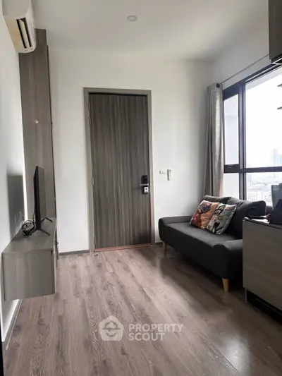 Modern living room with sleek design, large window, and cozy seating area in a high-rise apartment.