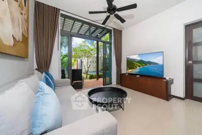 Spacious living room with modern decor and garden view, featuring a large TV and comfortable seating.