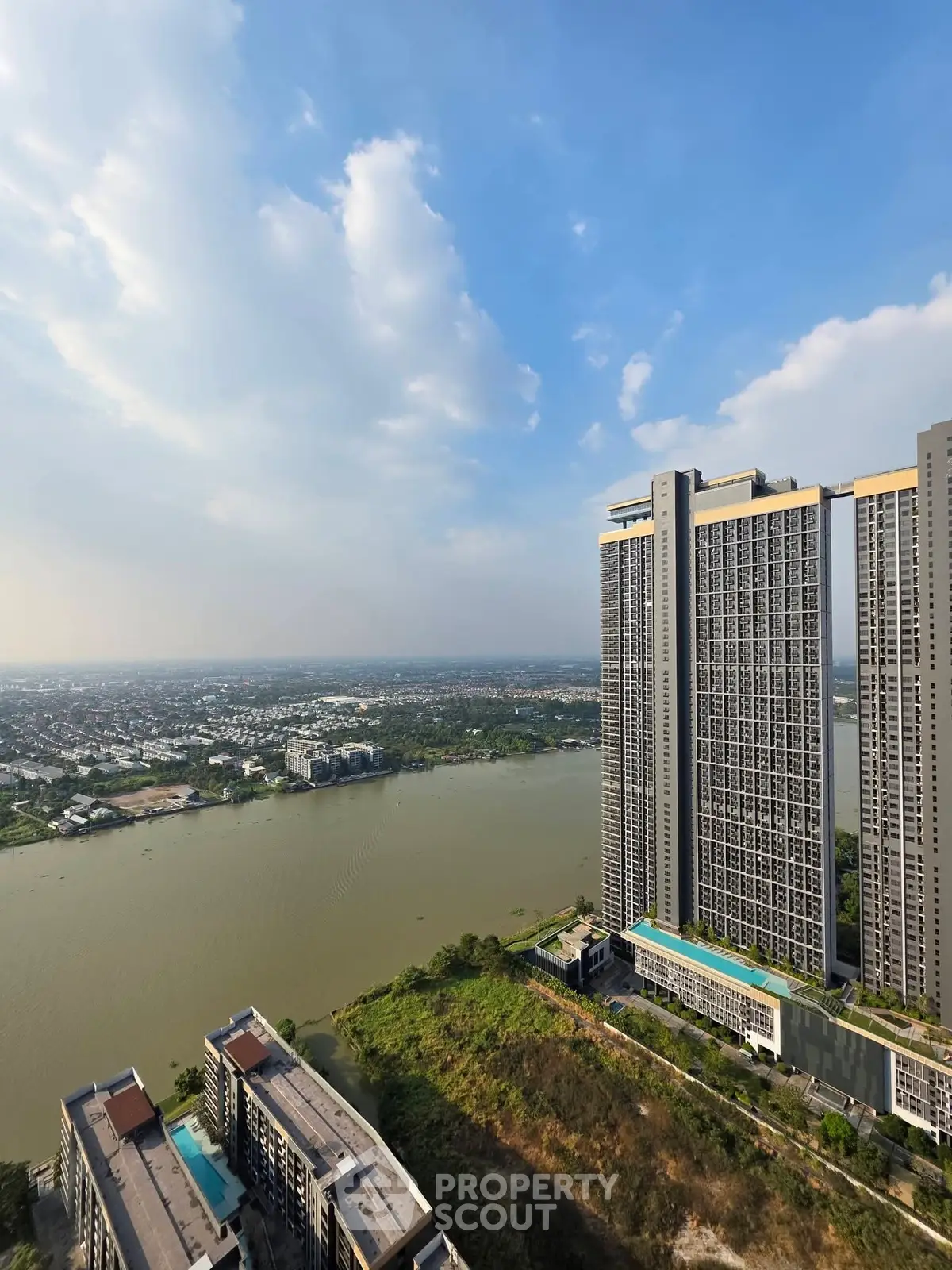 Stunning high-rise building with panoramic river view and lush greenery, perfect for luxury living.