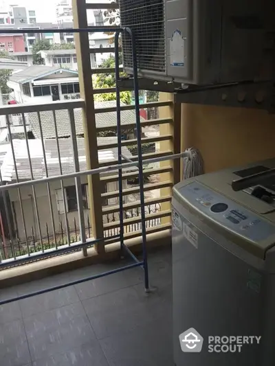 Compact balcony with washing machine and city view, ideal for urban living convenience.