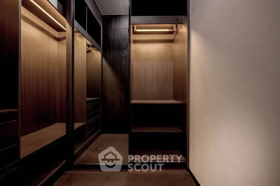 Luxurious walk-in closet with elegant wooden shelving and ambient lighting.
