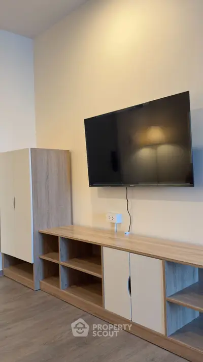 Modern living room with sleek TV setup and stylish wooden furniture.