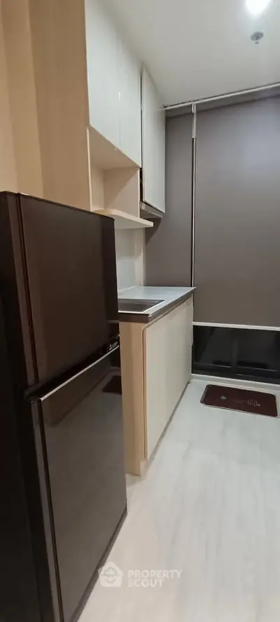 Modern kitchen with sleek cabinets and compact fridge in stylish apartment.