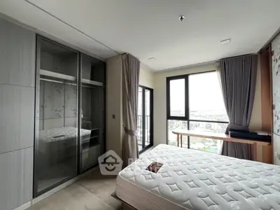 Modern bedroom with large windows and city view, featuring a comfortable bed and sleek wardrobe.