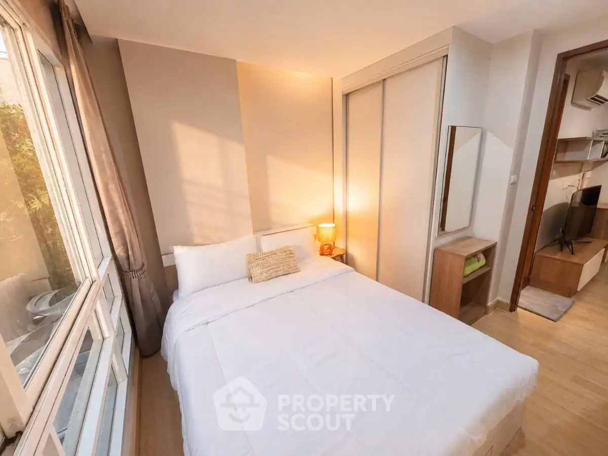 Cozy bedroom with large window and modern furnishings, perfect for relaxation and comfort.