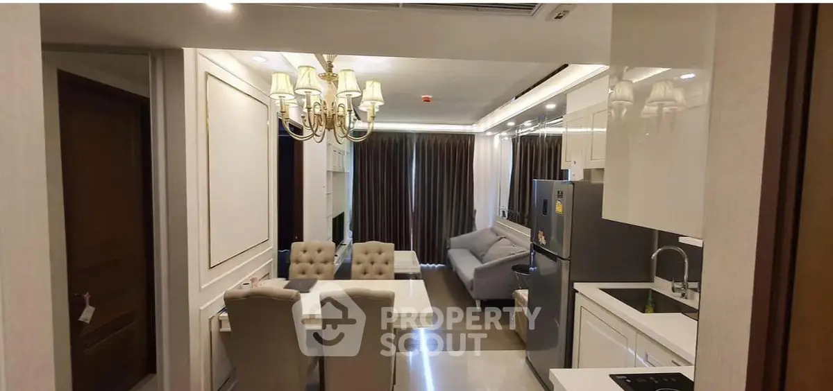 Luxurious open-plan kitchen and living room with elegant chandelier and modern furnishings.
