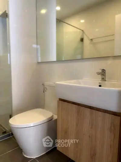 Modern bathroom with sleek fixtures and large mirror in contemporary apartment.