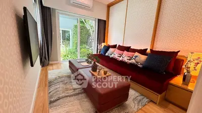 Stylish living room with modern decor and garden view, featuring a plush red sofa and elegant lighting.