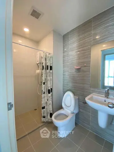 Modern bathroom with shower, toilet, and sink in a stylish tiled design.
