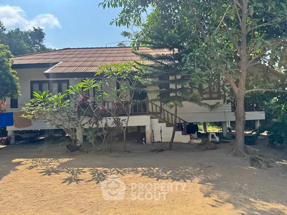 Charming elevated rural house with lush greenery and spacious yard, perfect for serene living.