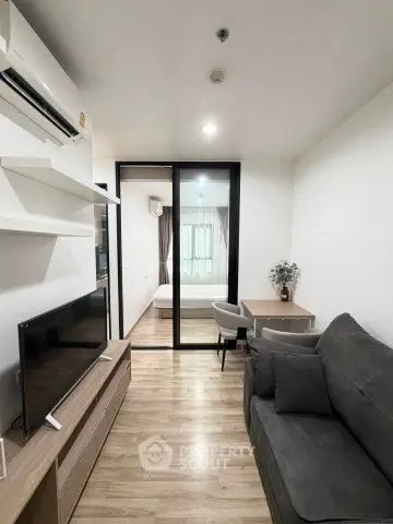 Modern living room with sleek furniture and sliding glass doors leading to a cozy bedroom.