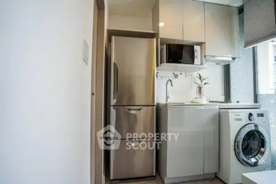 Compact modern kitchen with stainless steel fridge, microwave, and washing machine