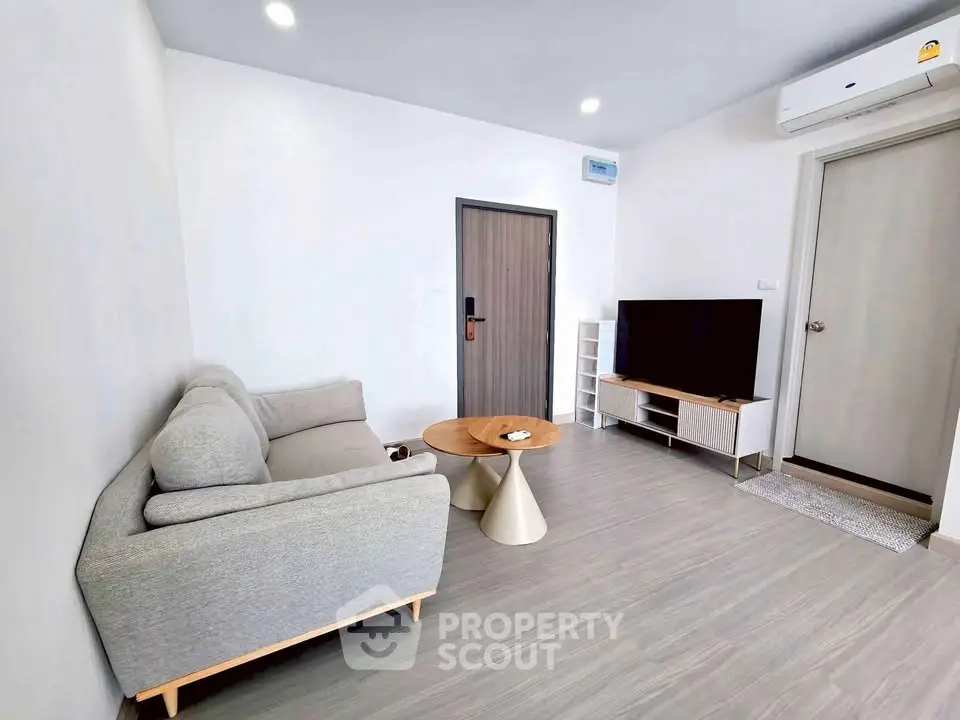 Modern living room with sleek furniture and minimalist design, featuring a cozy sofa and flat-screen TV.