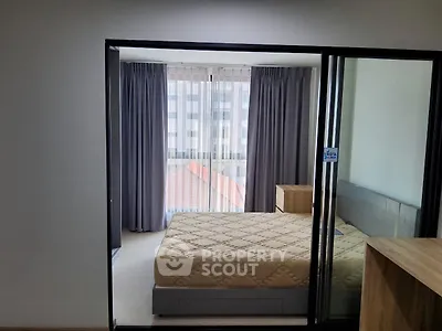 Modern bedroom with large window and stylish furnishings in a contemporary apartment.