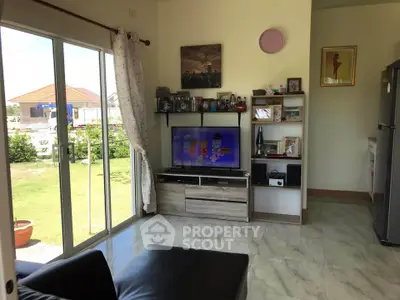 Cozy living room with sliding glass doors opening to a lush garden, featuring modern decor and entertainment setup.