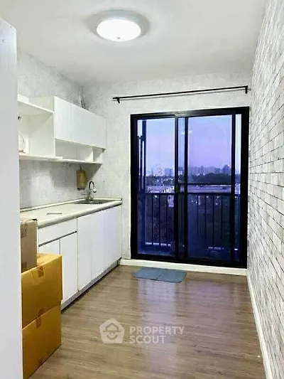 Bright kitchen with balcony view, featuring sleek white cabinets and modern design.