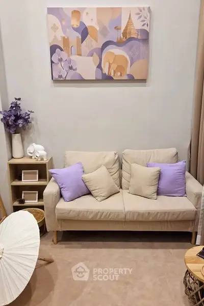 Cozy living room with beige sofa, purple cushions, and decorative wall art, perfect for relaxation.
