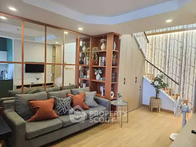Stylish living room with modern decor and open shelving, featuring cozy seating and elegant lighting.