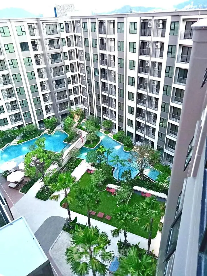 Stunning aerial view of modern apartment complex with lush gardens and inviting swimming pools.