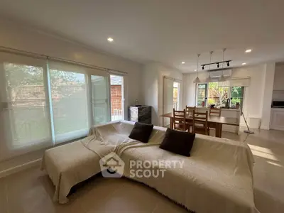 Spacious living room with open kitchen and garden view, perfect for family gatherings.