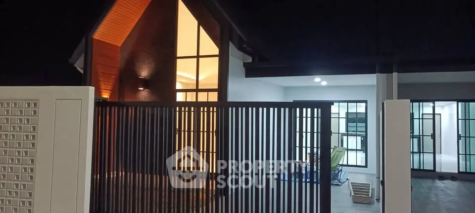 Modern house exterior with sleek design and large windows at night.