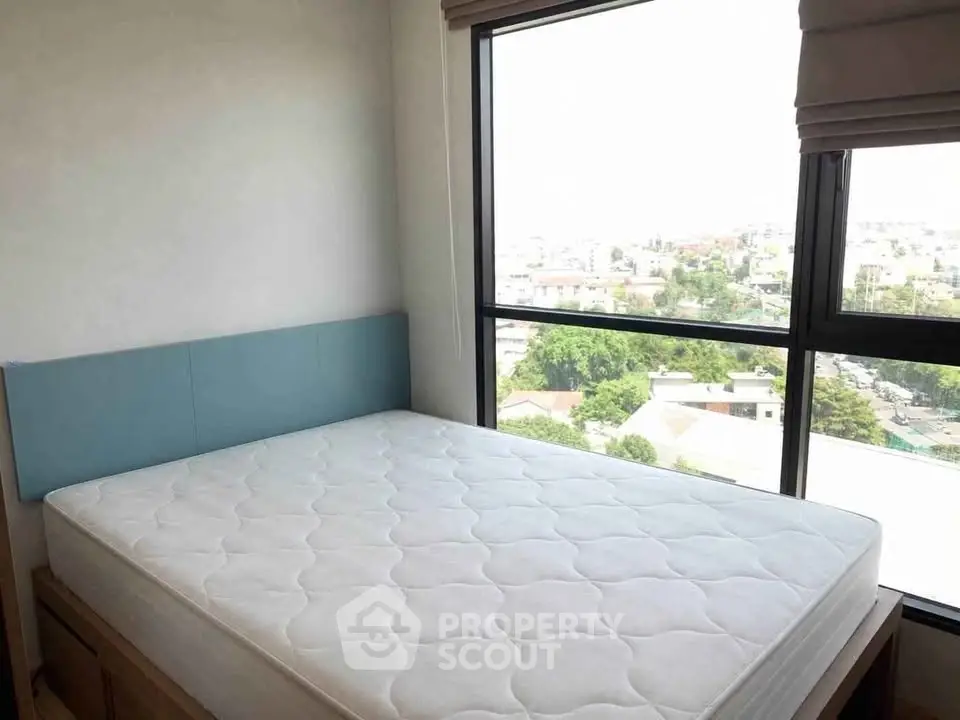 Bright bedroom with large window offering stunning city views and natural light.
