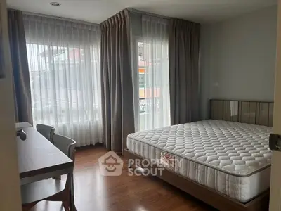 Bright bedroom with large windows and wooden flooring, featuring a comfortable bed and a stylish desk.