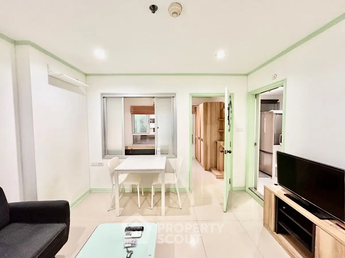 Modern living room with dining area and kitchen view, featuring sleek furniture and bright lighting.