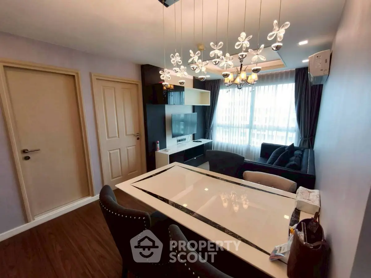 Modern living room with elegant chandelier and stylish furniture, featuring a cozy seating area and large window.