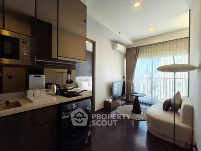 Modern open-layout living room with kitchen, featuring sleek appliances and cozy seating area.