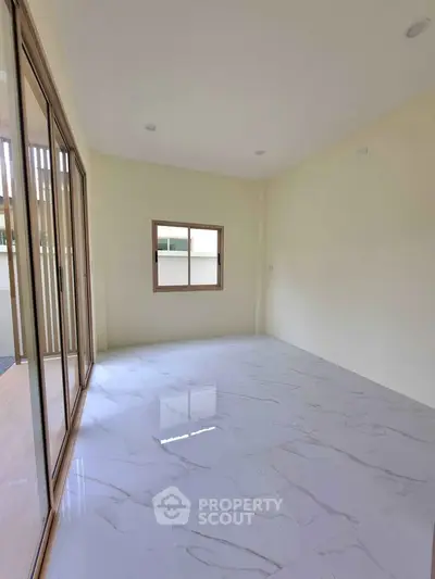 Spacious empty room with marble flooring and large windows for natural light.
