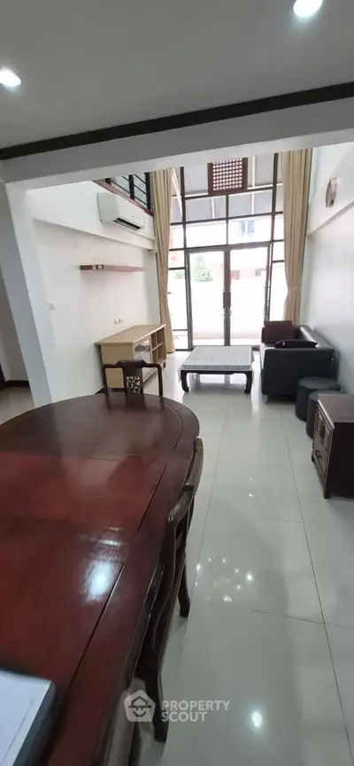 Spacious living room with high ceilings and modern furniture, featuring large windows for natural light.