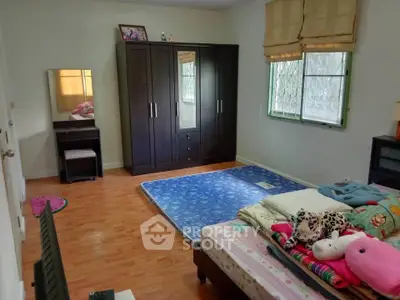 Cozy bedroom with wooden flooring, wardrobe, and large window for natural light.