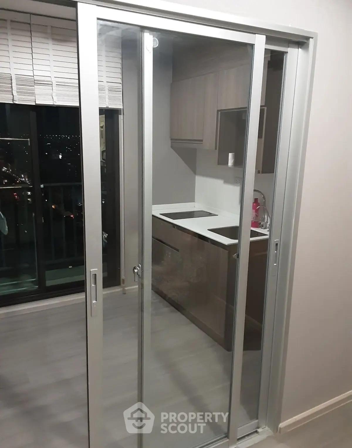 Modern kitchen with sliding glass doors and city view, sleek cabinetry and compact design.