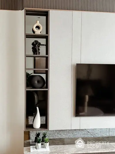 Elegantly designed modern living room with a sleek built-in wall unit, showcasing a flat-screen TV and stylish decorative shelves.