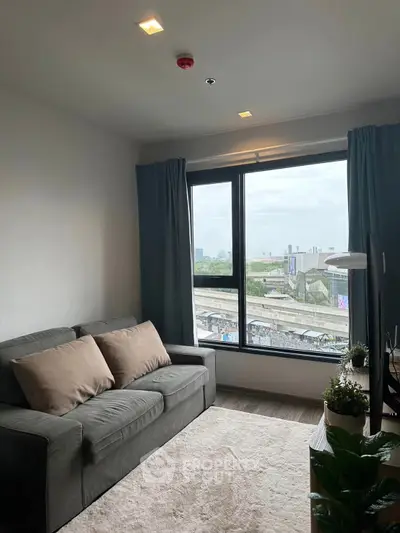 Cozy living room with large window offering city view, modern sofa, and stylish decor.