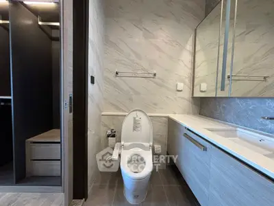 Modern bathroom with sleek design and spacious layout, featuring a stylish toilet and elegant vanity.