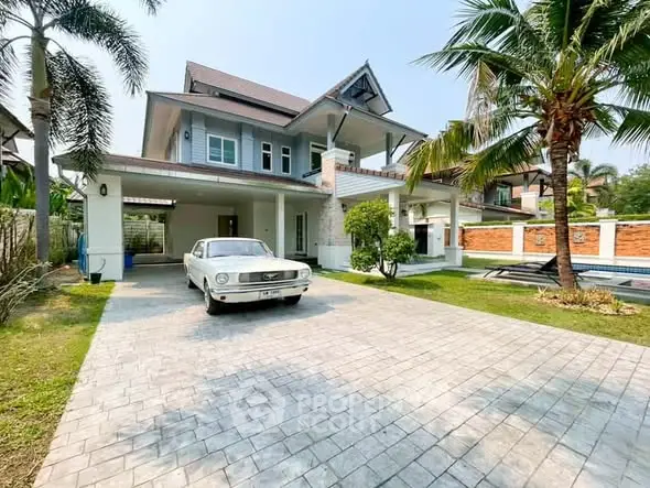 Charming two-story house with vintage car in driveway, surrounded by lush greenery and palm trees.