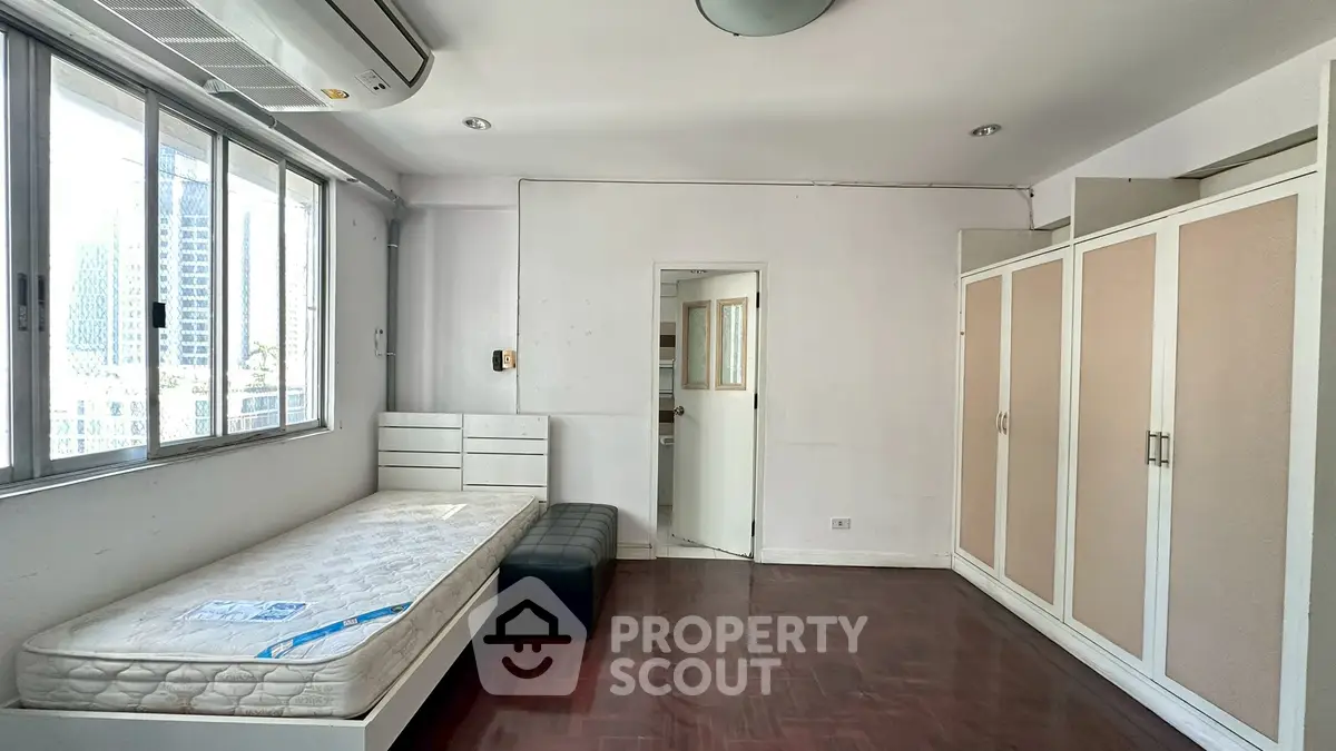 Spacious bedroom with large windows and ample storage in urban apartment